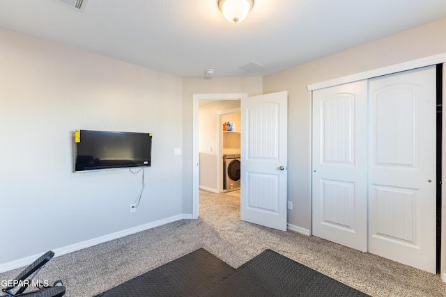 unfurnished bedroom featuring light carpet, a closet, and washer / dryer