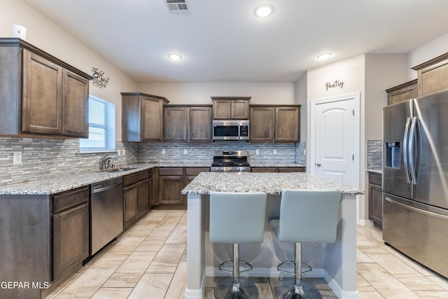 kitchen with decorative backsplash, dark brown cabinetry, stainless steel appliances, and a kitchen island