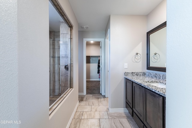 bathroom featuring a tile shower and vanity