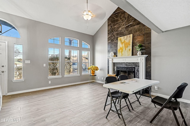 office space with ceiling fan, a fireplace, and high vaulted ceiling