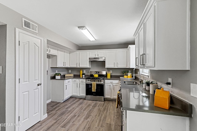 kitchen featuring sink, stainless steel gas range oven, and white cabinets