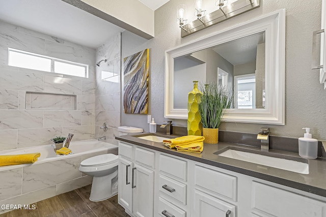 full bathroom featuring vanity, tiled shower / bath combo, and toilet