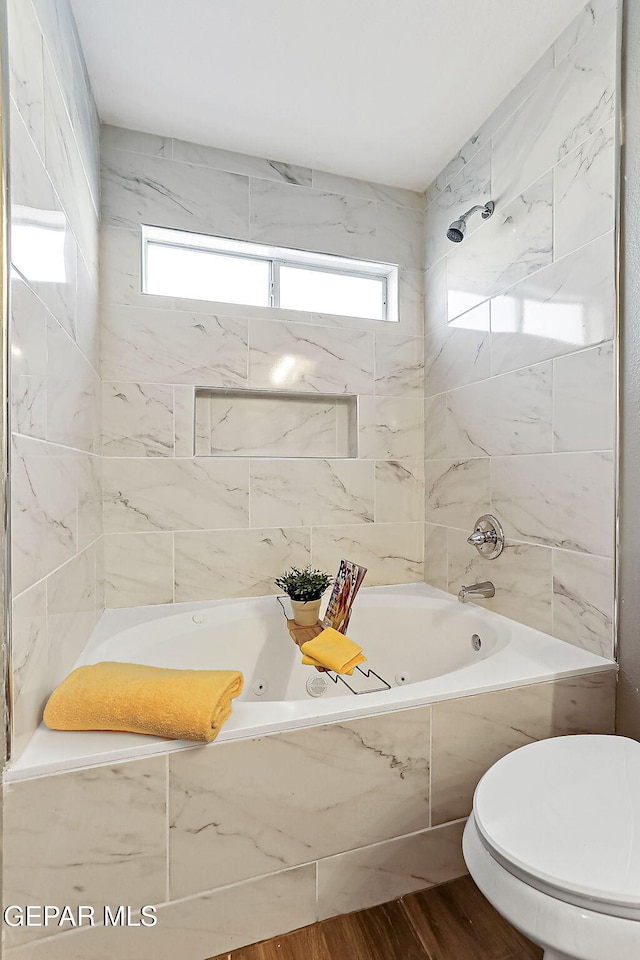 bathroom featuring tiled shower / bath, plenty of natural light, hardwood / wood-style floors, and toilet