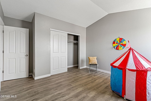 bedroom featuring hardwood / wood-style flooring, lofted ceiling, a textured ceiling, and a closet