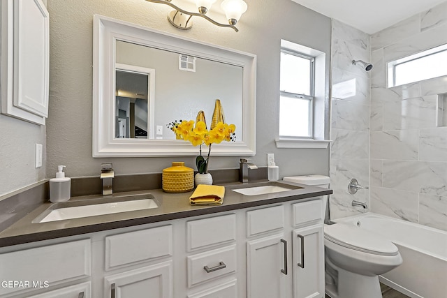 full bathroom with tiled shower / bath, vanity, toilet, and a wealth of natural light