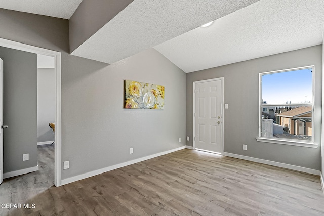 entryway featuring lofted ceiling, light hardwood / wood-style floors, and a textured ceiling