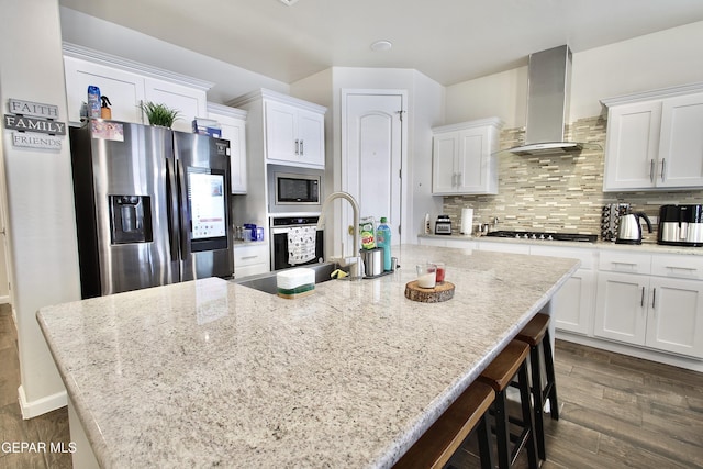 kitchen with stainless steel appliances, a spacious island, and wall chimney exhaust hood