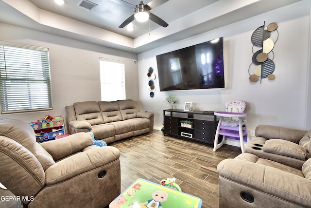 living room with ceiling fan and a tray ceiling