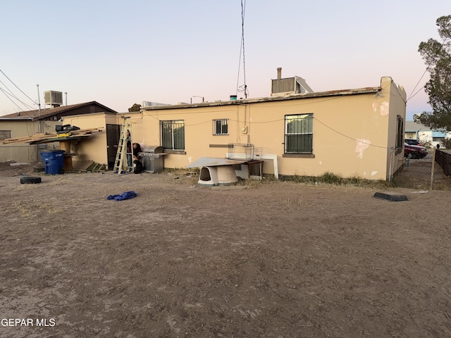 back house at dusk featuring central AC