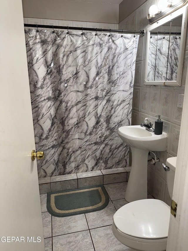 bathroom featuring walk in shower, tile patterned floors, toilet, and tile walls