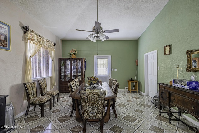 dining space featuring ceiling fan, a textured ceiling, and vaulted ceiling