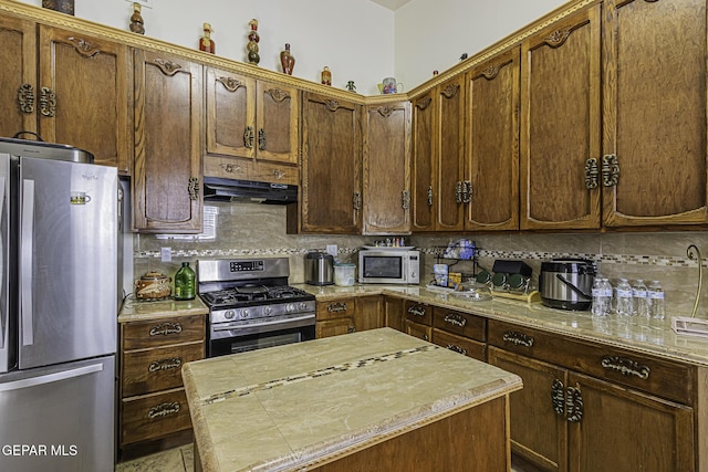 kitchen featuring tasteful backsplash, light stone countertops, stainless steel appliances, and a kitchen island