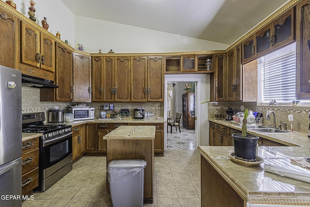 kitchen with vaulted ceiling, a kitchen island, decorative backsplash, sink, and stainless steel appliances