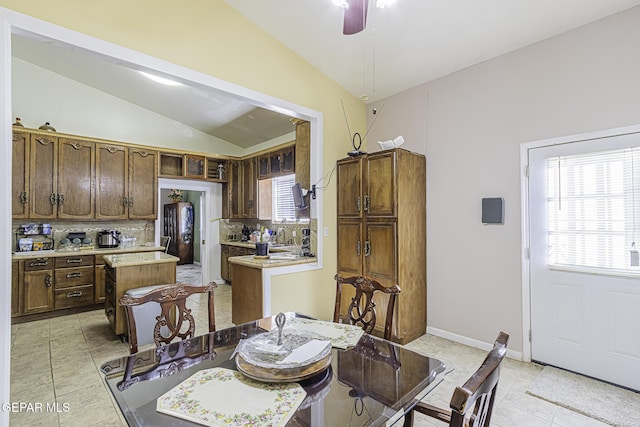 tiled dining space featuring ceiling fan and vaulted ceiling