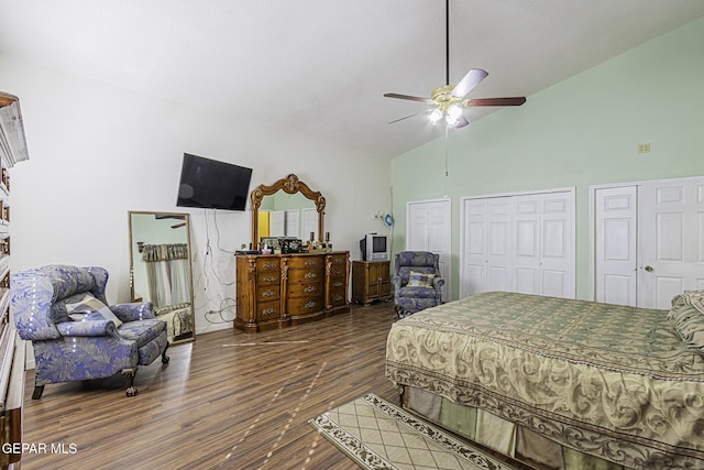 bedroom with dark wood-type flooring, ceiling fan, multiple closets, and high vaulted ceiling