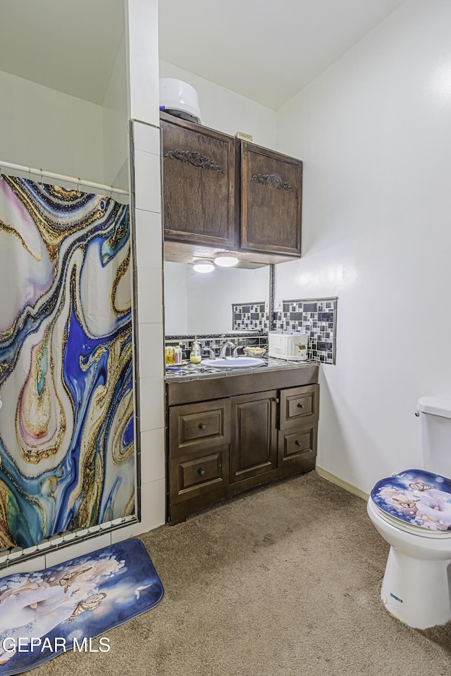 bathroom featuring toilet, vanity, walk in shower, and tasteful backsplash