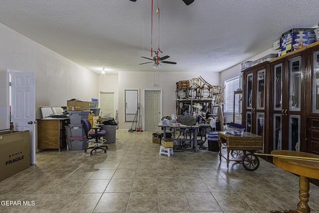 interior space featuring ceiling fan, tile patterned floors, and a textured ceiling