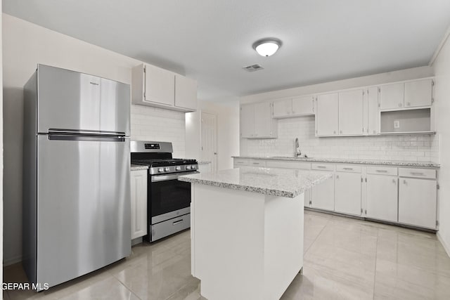 kitchen with stainless steel appliances, a sink, visible vents, white cabinetry, and a center island