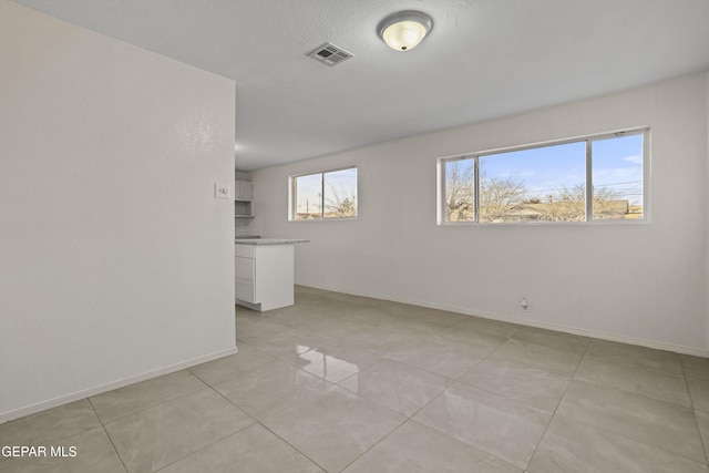 empty room featuring visible vents, a textured ceiling, and baseboards