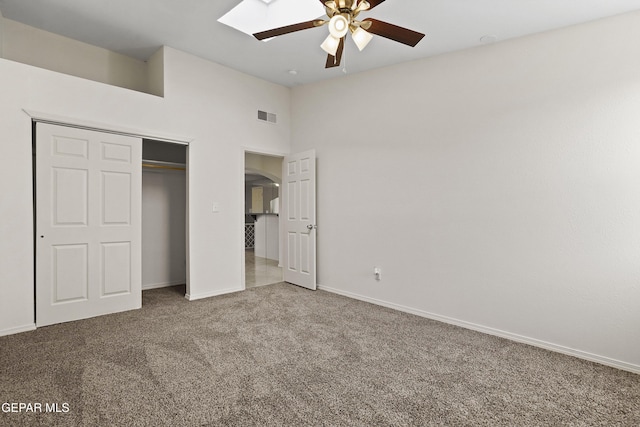 unfurnished bedroom with ceiling fan, a closet, carpet flooring, and a high ceiling