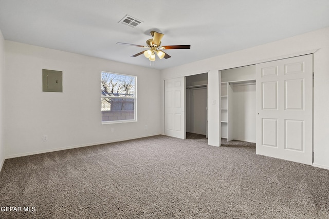 unfurnished bedroom with ceiling fan, two closets, carpet floors, and electric panel