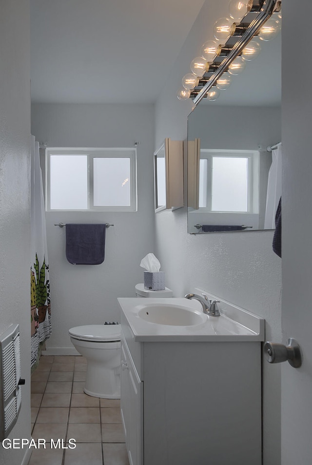 bathroom with toilet, heating unit, tile patterned floors, and vanity