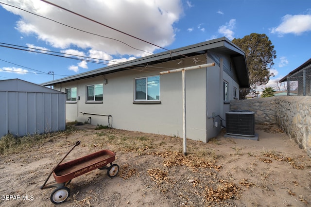 back of house featuring central air condition unit and a storage unit