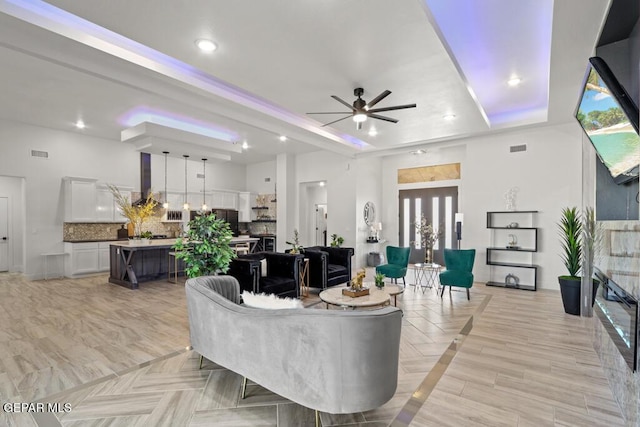 living room featuring ceiling fan and a tray ceiling