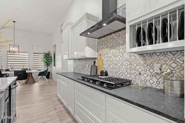 kitchen featuring white cabinets, wall chimney exhaust hood, stainless steel gas cooktop, and pendant lighting