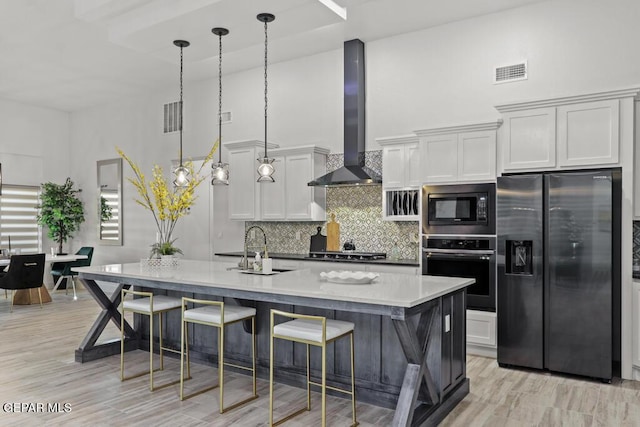 kitchen featuring stainless steel appliances, white cabinetry, wall chimney exhaust hood, and a towering ceiling