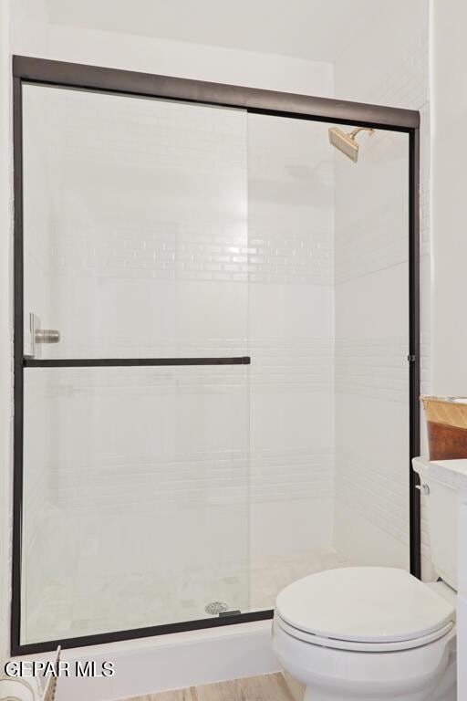 bathroom with a shower with shower door and toilet