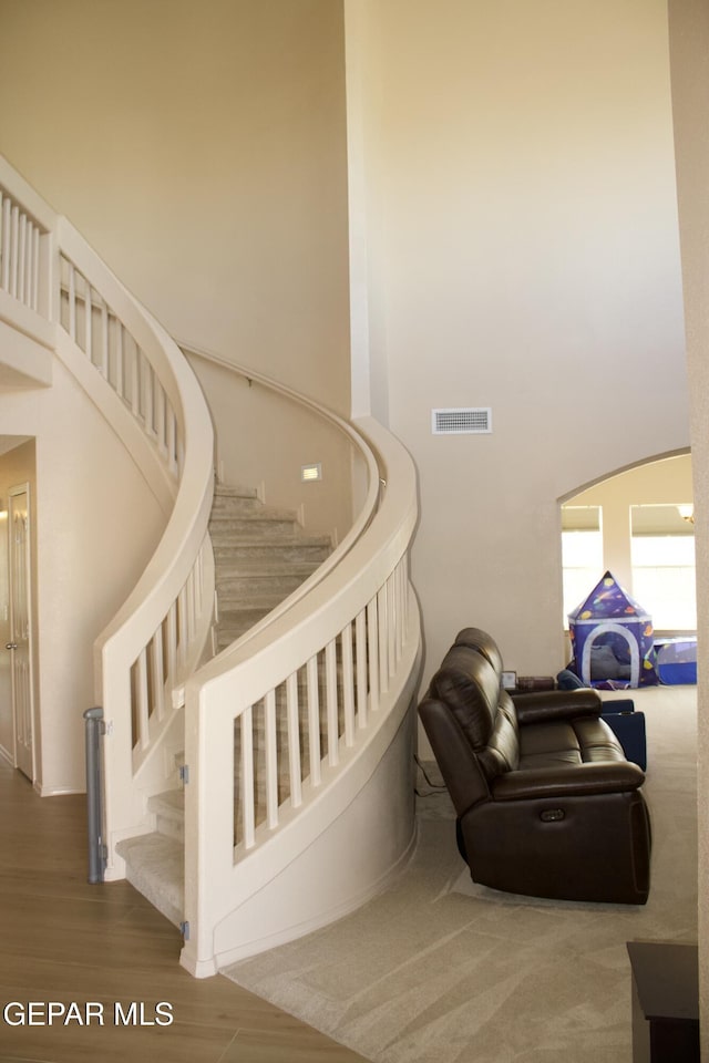 stairs featuring hardwood / wood-style flooring and a towering ceiling