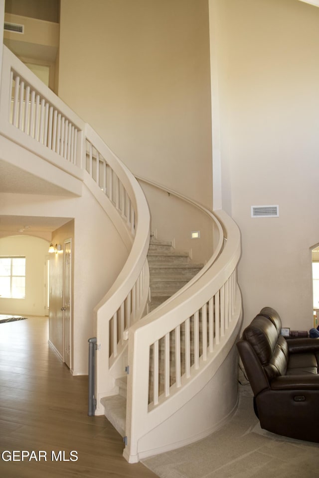 stairway with a towering ceiling and hardwood / wood-style flooring