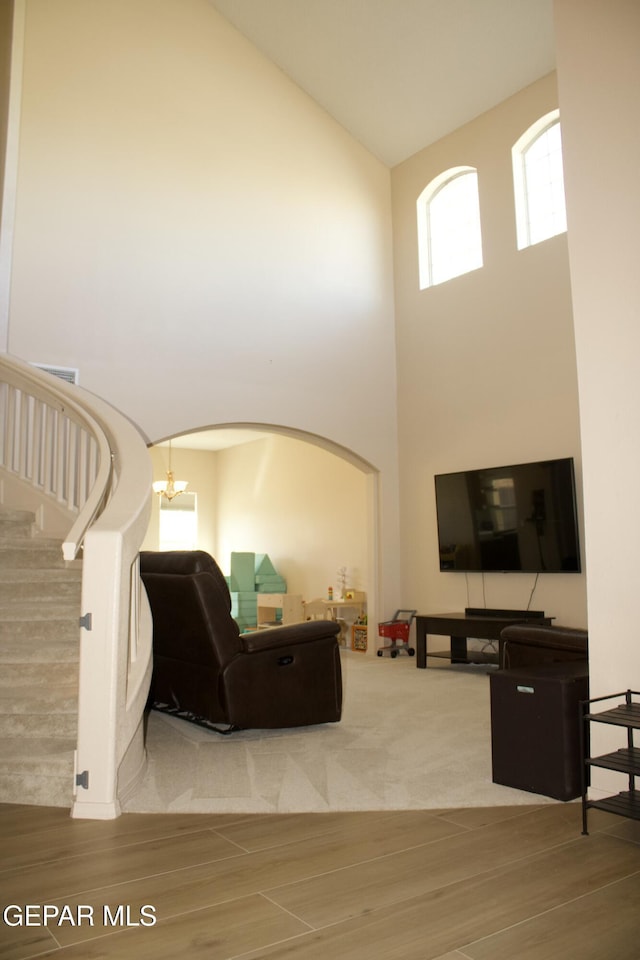 living room featuring wood-type flooring, a notable chandelier, and high vaulted ceiling