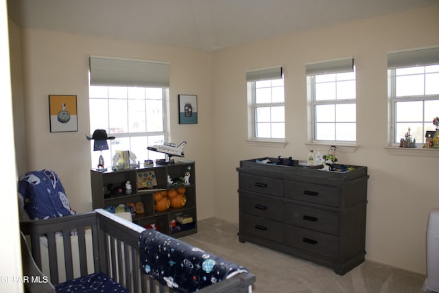 carpeted bedroom with multiple windows and a crib