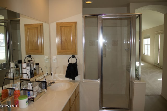 bathroom featuring a shower with door and vanity