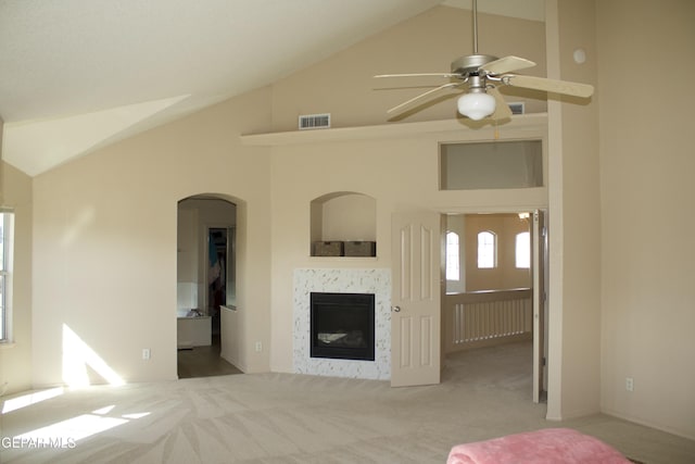 unfurnished living room featuring ceiling fan, high vaulted ceiling, light colored carpet, and a fireplace