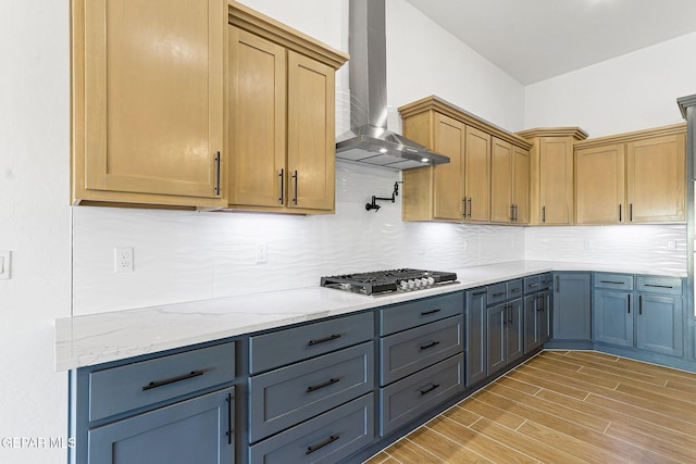 kitchen with backsplash, light stone countertops, gray cabinets, wall chimney range hood, and stainless steel gas cooktop