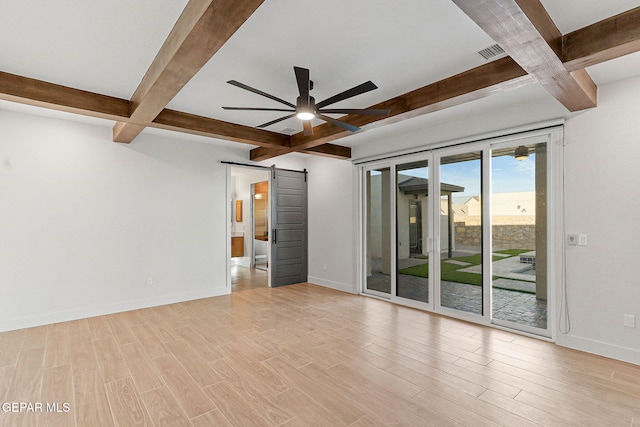 empty room featuring light hardwood / wood-style floors, ceiling fan, beamed ceiling, and a barn door