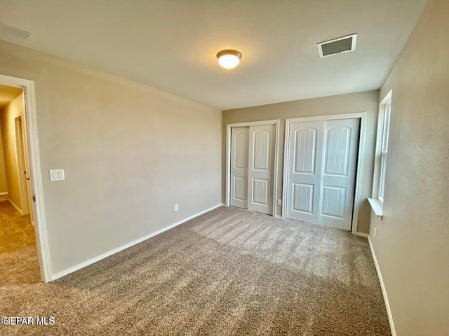 unfurnished bedroom with two closets and carpet flooring