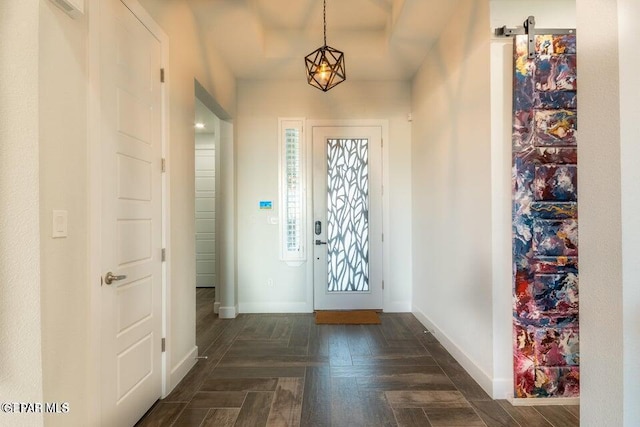 foyer featuring dark parquet flooring, an inviting chandelier, and a barn door