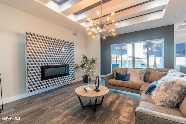 living room featuring a tiled fireplace, a notable chandelier, and dark hardwood / wood-style floors