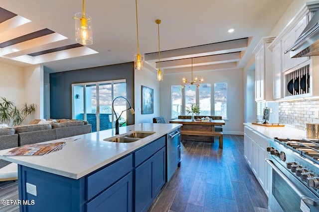 kitchen featuring sink, decorative light fixtures, white cabinetry, blue cabinetry, and a kitchen island with sink