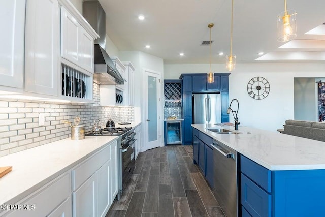 kitchen featuring appliances with stainless steel finishes, blue cabinetry, pendant lighting, decorative backsplash, and white cabinetry