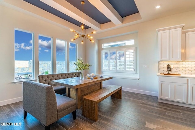 dining space with a healthy amount of sunlight, dark hardwood / wood-style flooring, an inviting chandelier, and beamed ceiling