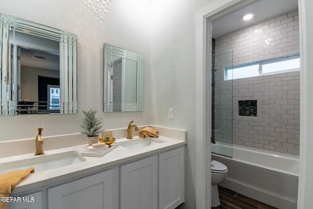 full bathroom with wood-type flooring, vanity, tiled shower / bath combo, and toilet