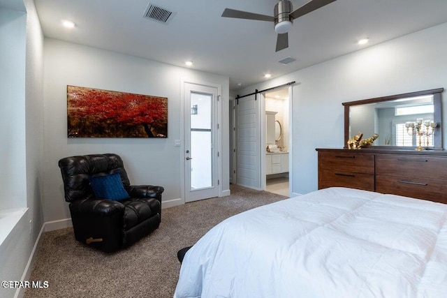 bedroom with ensuite bathroom, light colored carpet, ceiling fan, and a barn door