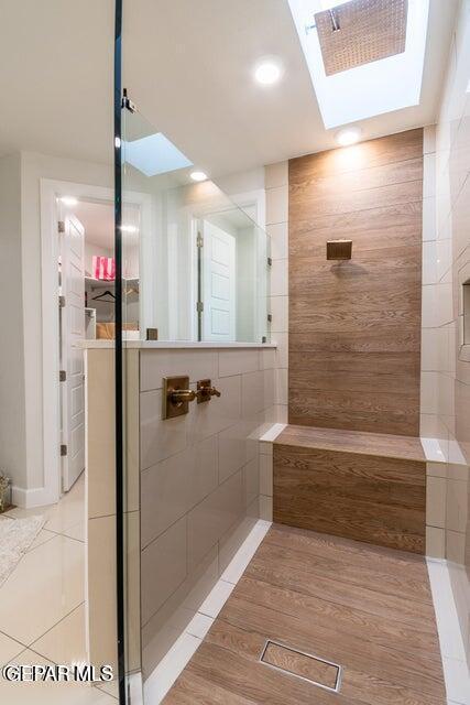 bathroom featuring walk in shower, tile patterned floors, and a skylight