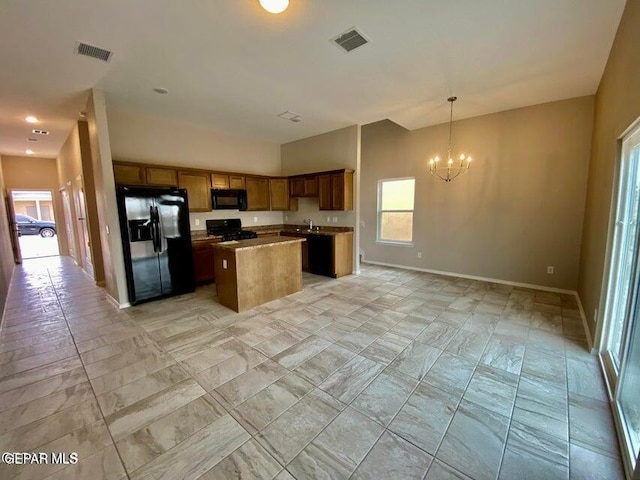 kitchen featuring hanging light fixtures, a notable chandelier, black appliances, a kitchen island, and sink