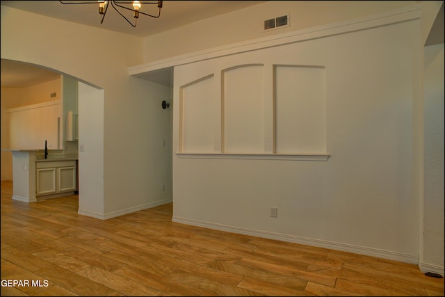 spare room featuring sink, an inviting chandelier, and light hardwood / wood-style flooring